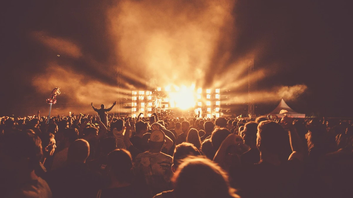 A crowd with hands raised at a live music concert with stage lights in London
